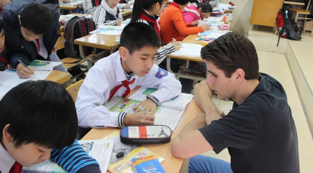 A Projects Abroad Teaching volunteer in Vietnam helps a students with his classwork A volunteer helps his students in class during his teaching work experience in Vitenam